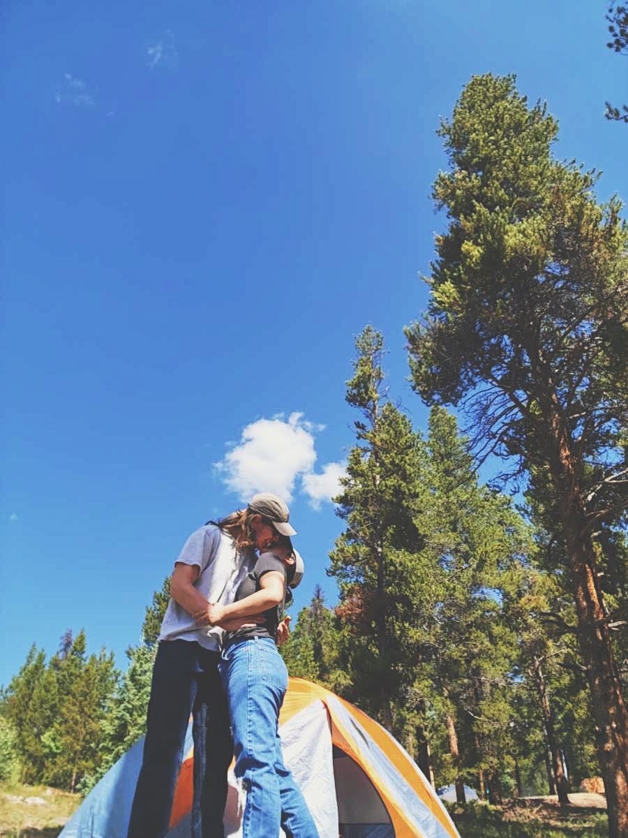 Rachel and her boyfriend hugging dearly in front of their tent while camping